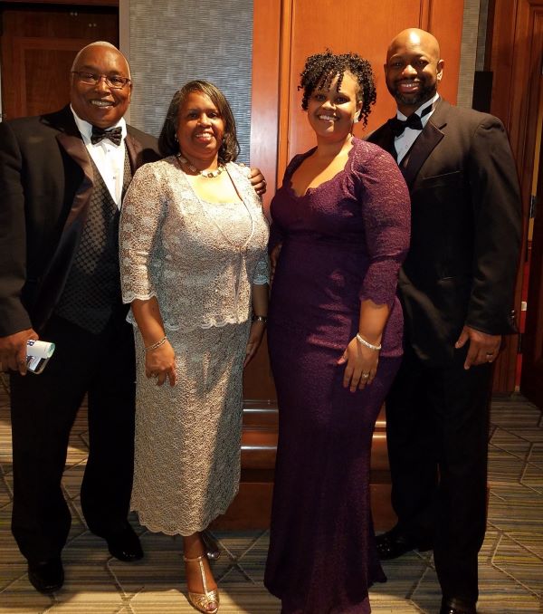 Dr. Brooks in formalwear, standing beside his wife and mentor. 